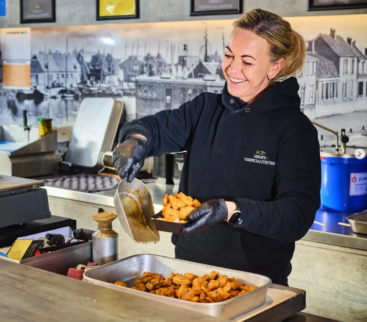 Medewerkster schept vers gebakken kibbeling in een bakje